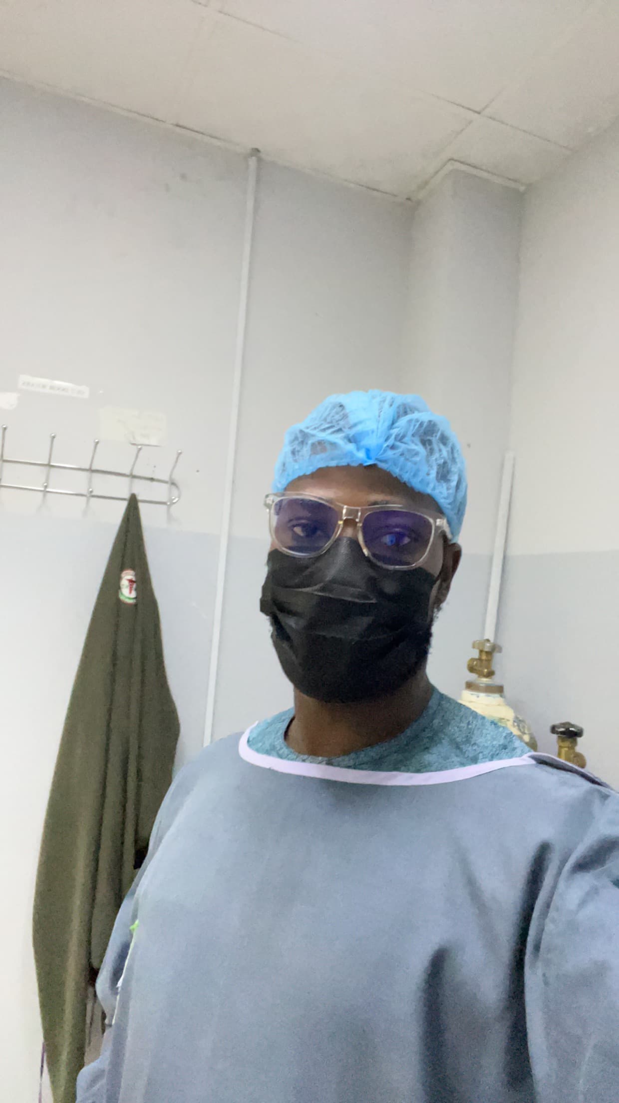 Onyekachi Nwakaihe in a surgical gown, cap and mask during a hospital visit as a caregiver